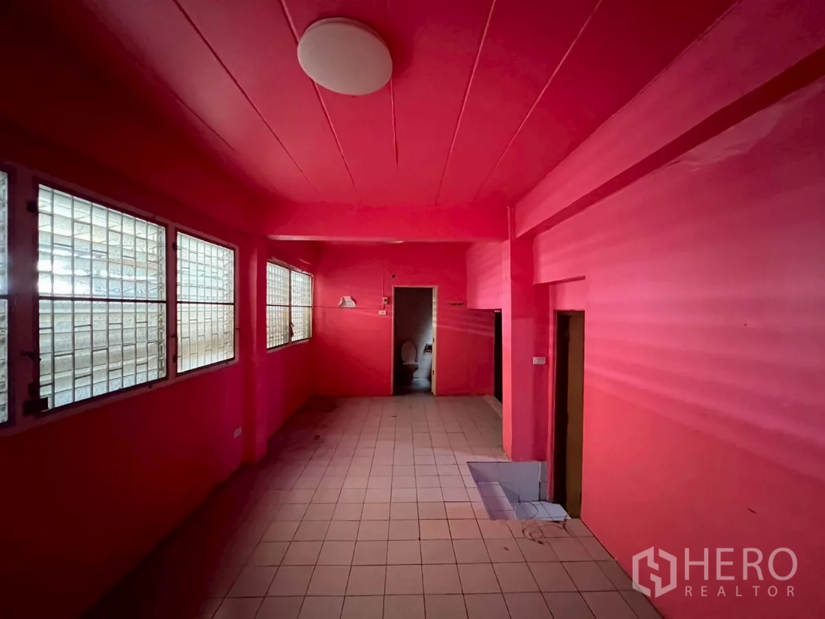 Shophouse for rent in Watthana, Bangkok - Utility room with tiled floor, barred windows, and doorway to a restroom.