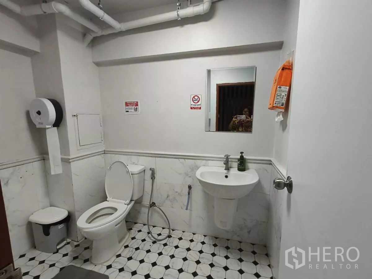 Shophouse for rent in Watthana, Bangkok - Clean restroom with toilet, sink and marble-look wall and floor tiles.