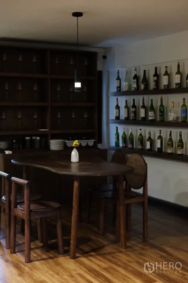 零售空间 for rent in Sathon, Bangkok - 私密用餐角落，圆形木桌、吊灯与陈列酒瓶和酒杯的层架。