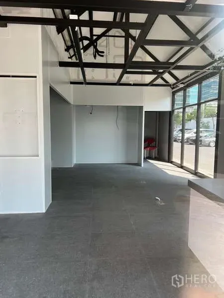 Retail Space for rent - Open-plan interior with high ceilings, black steel trusses and floor-to-ceiling windows.