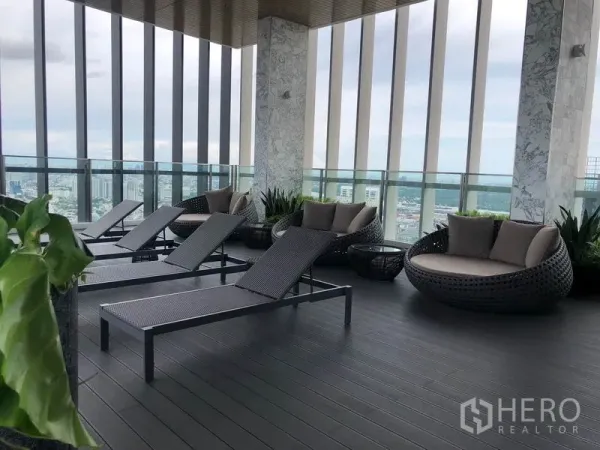 Condominium for rent in Khlong Toei, Bangkok - Rooftop lounge with sun loungers and daybeds overlooking Bangkok skyline.