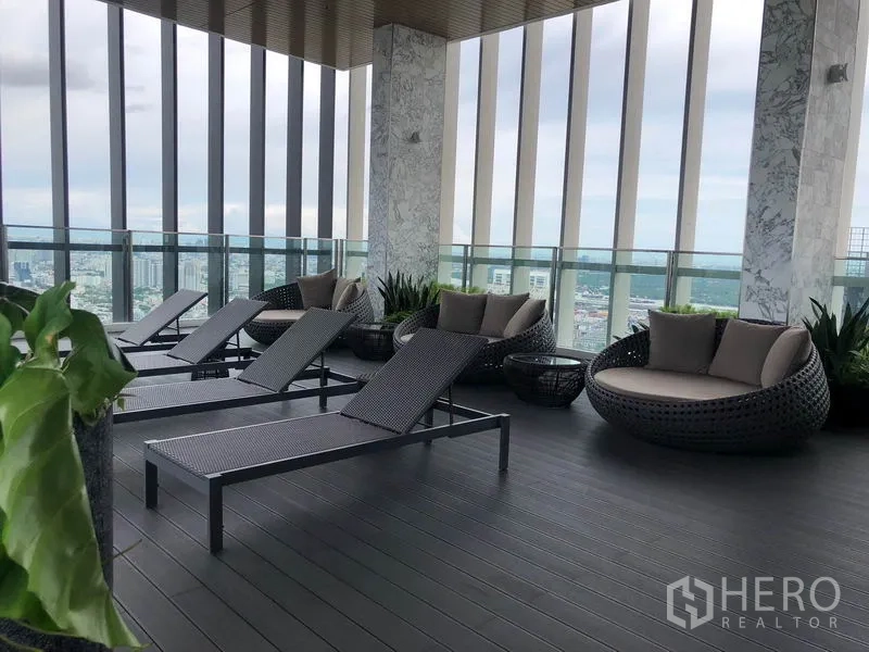 Condominium for rent in Khlong Toei, Bangkok - Rooftop lounge with sun loungers and daybeds overlooking Bangkok skyline.