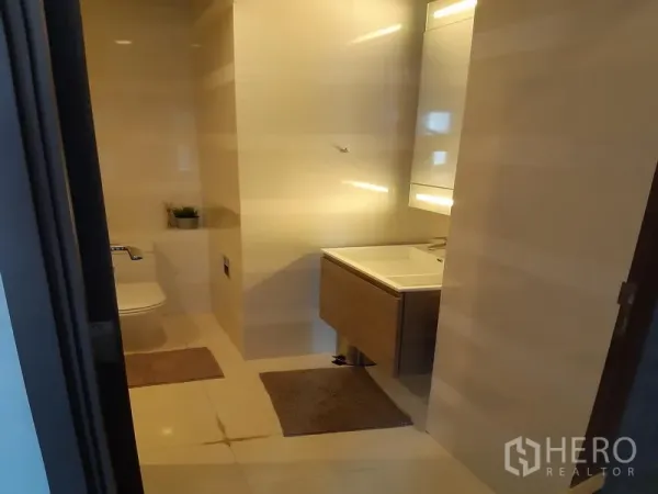 Condominium for rent in Khlong Toei, Bangkok - Modern bathroom with floating vanity, large mirror and light-toned tiles