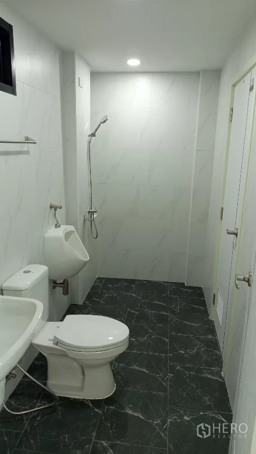 Warehouse for rent or sale in Lam Luk Ka, Pathum Thani - Clean bathroom with toilet, urinal, sink, and shower on tiled walls and floor.