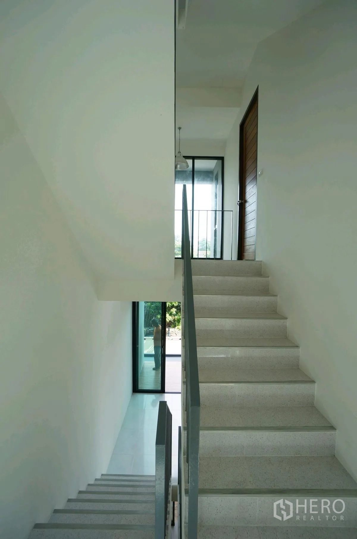 Home Office for rent in Chatuchak, Bangkok - Bright stairwell with white steps, metal railing, and glass door to the outside.