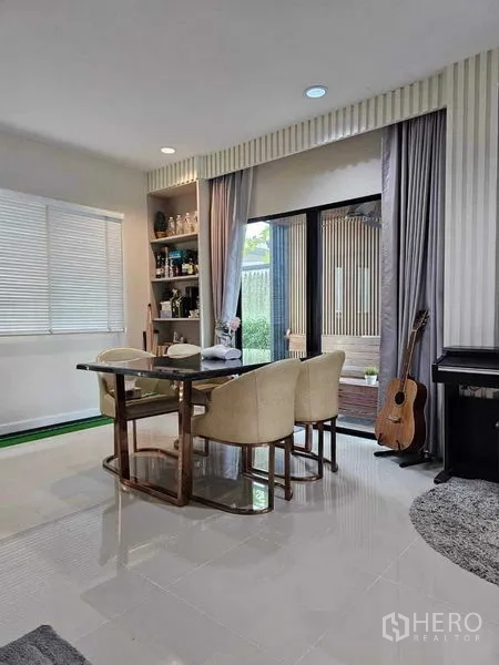 Detached House for sale in Khan Na Yao, Bangkok - Bright dining area with built-in shelving, sliding glass doors to the garden, and a piano.