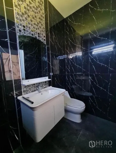 独立式住宅 出售在Sai Mai, Bangkok - 深色卫浴，马赛克装饰带、悬挂式浴柜与马桶。