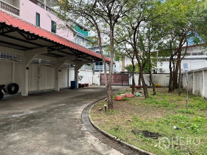 独立式住宅 出租在Sathon, Bangkok - 红瓦顶车棚与草地及成树并排的庭院。