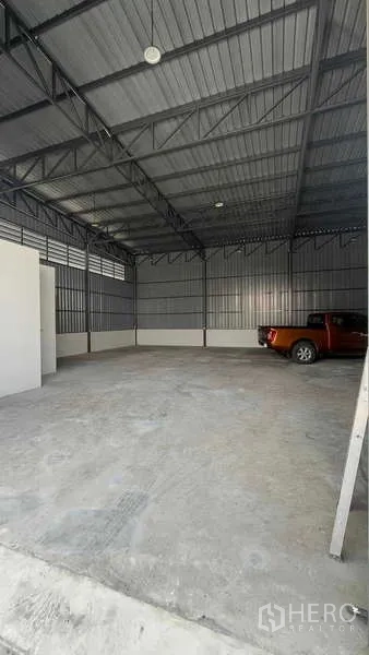 Warehouse for rent in Bang Khen, Bangkok - Spacious warehouse interior with steel truss roof, concrete floor and a pickup parked to the side.