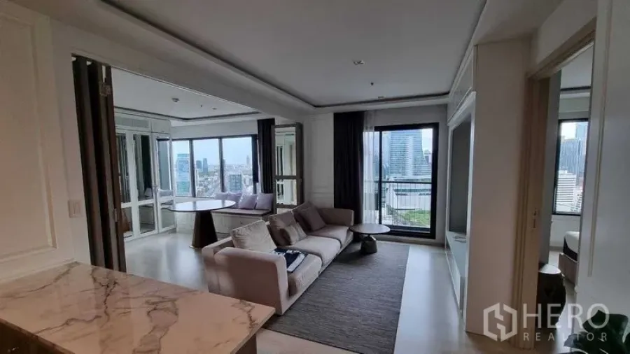 Condominium for sale in Pathum Wan, Bangkok - Living area seen from the kitchen with sofa, balcony and city views