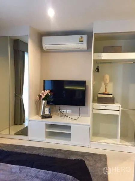 Condominium for rent in Khlong Toei, Bangkok - Bedroom wall with TV console, air-conditioning and built-in open wardrobe.