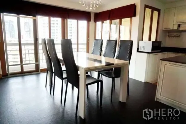 Condominium for rent in Watthana, Bangkok - Dining table for six beside floor-to-ceiling windows with city views and balcony access.