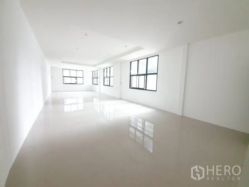 Warehouse for rent in Bang Khen, Bangkok - Expansive interior perspective highlighting ample loading space and multiple roller doors.