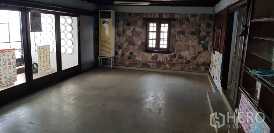 Townhouse for rent in Khlong Toei, Bangkok - Large ground-floor room with stone feature wall and glass doors in a Phra Khanong townhouse.