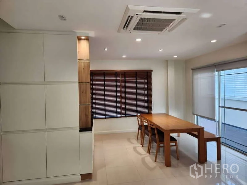 Detached House for rent in Sathon, Bangkok - Dining nook with wooden table, window blinds, and large windows.