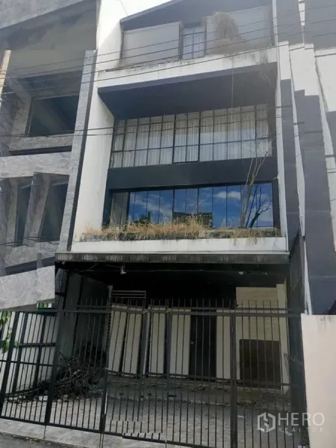 Home Office for rent in Watthana, Bangkok - Multi-storey home office facade with black-and-white exterior, gated parking and a balcony planter.