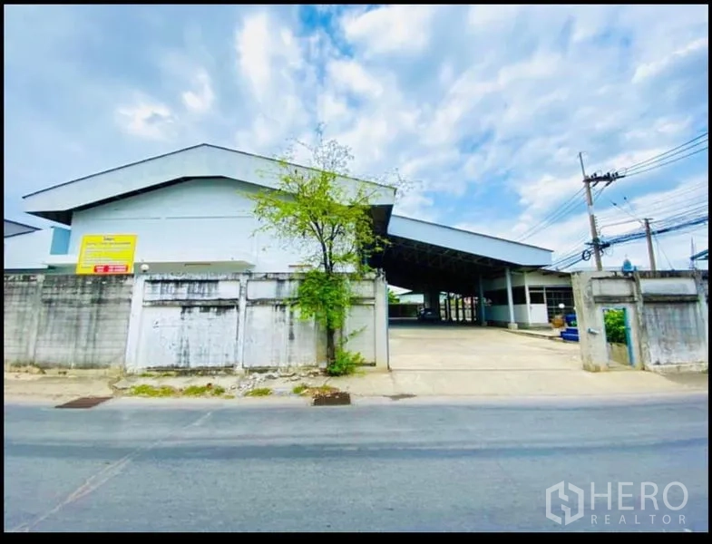 Factory for rent in Sam Phran, Nakhon Pathom - Street-facing gated factory entrance with a wide driveway and perimeter wall.