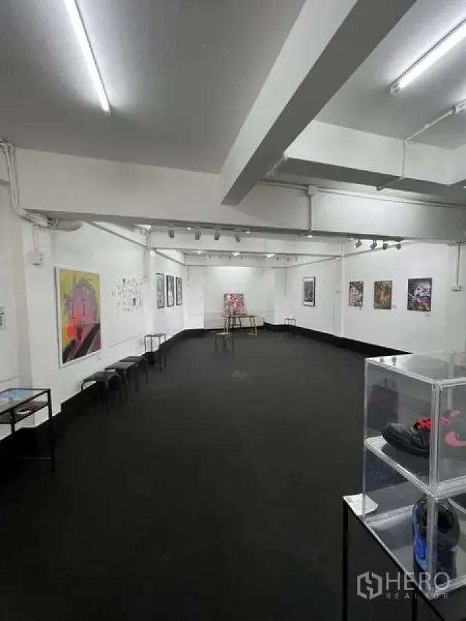 Shophouse for rent in Khlong Toei, Bangkok - Exhibition room with track lights, framed artworks and a clear display cabinet.