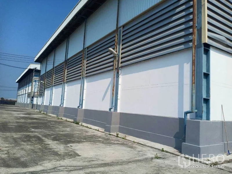 Warehouse for rent in Bang Bo, Samut Prakan - Side facade with continuous ventilation louvers and exterior light fixtures.