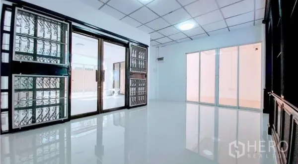 Townhouse for sale - Secondary living room with metal-grille sliding doors and reflective flooring.