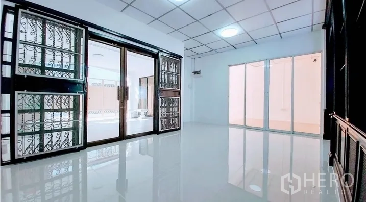 Townhouse for sale - Secondary living room with metal-grille sliding doors and reflective flooring.