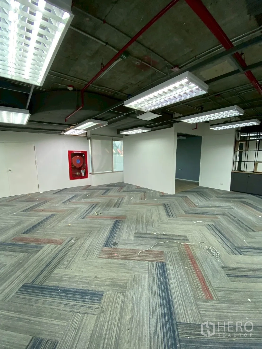 Office Space for rent in Watthana, Bangkok - Open area with safety equipment cabinet, carpet tiles, and drop-in light panels.