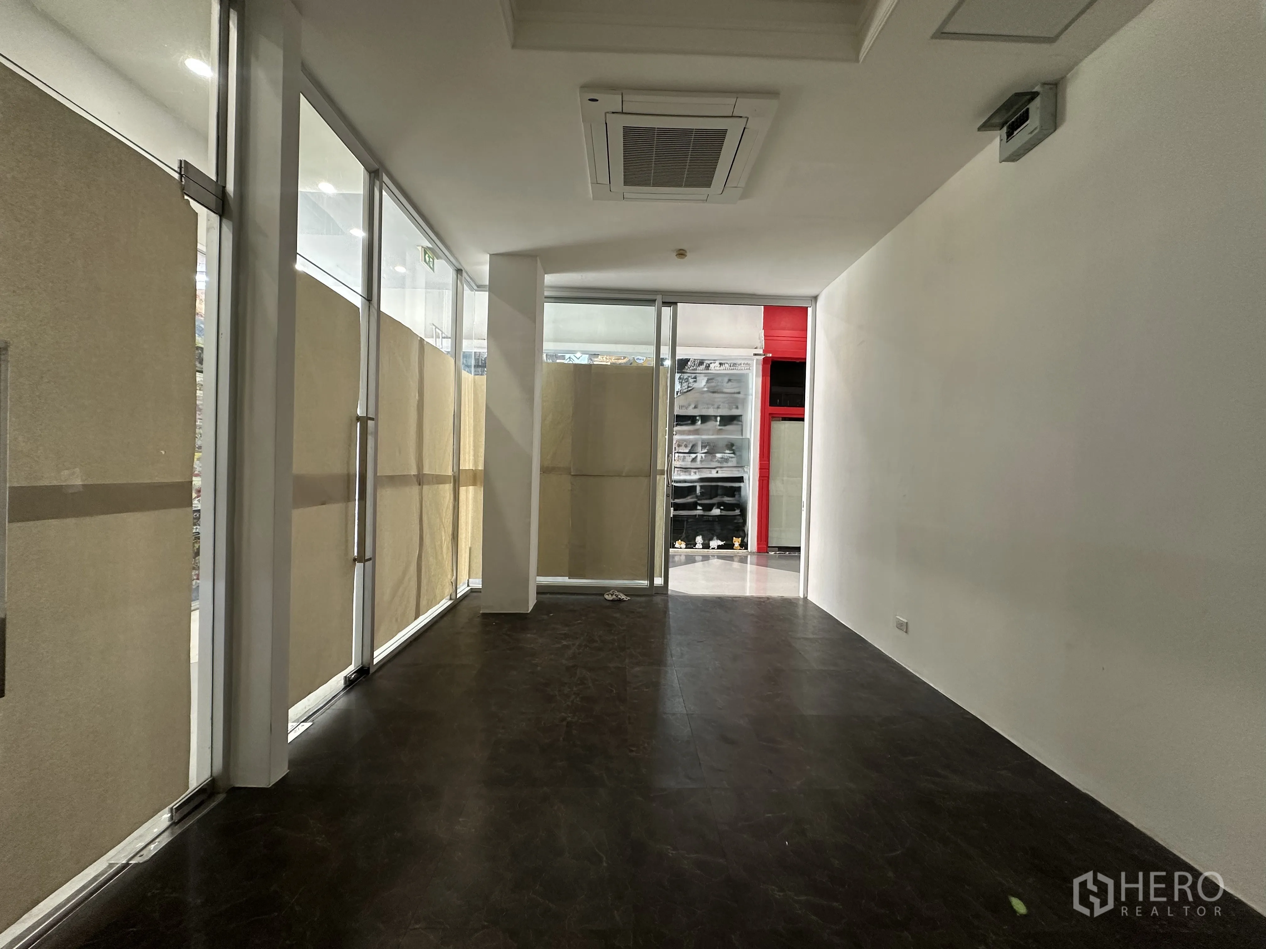 零售空间 for rent in Khlong Toei, Bangkok - 沿店内望向外部的视角，可见玻璃门、白色墙面与走廊景致。