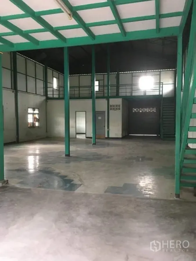 Warehouse for rent in Saphan Sung, Bangkok - Spacious warehouse interior with green steel columns, mezzanine level, and concrete floor.