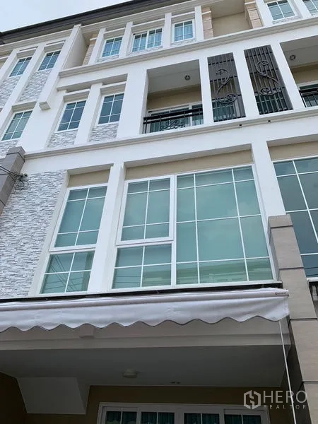 Townhouse for rent in Bang Na, Bangkok - Multi-storey townhouse facade with large grid windows and small balconies