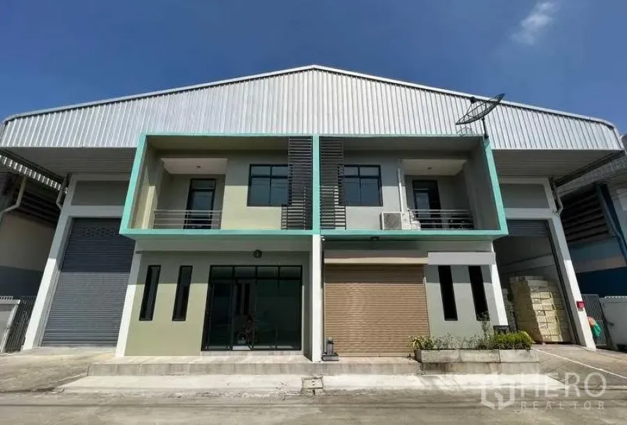 Factory for rent or sale in Mueang Samut Sakhon, Samut Sakhon - Modern factory exterior with two-storey office, large roller shutter and glass entrance under a metal roof.