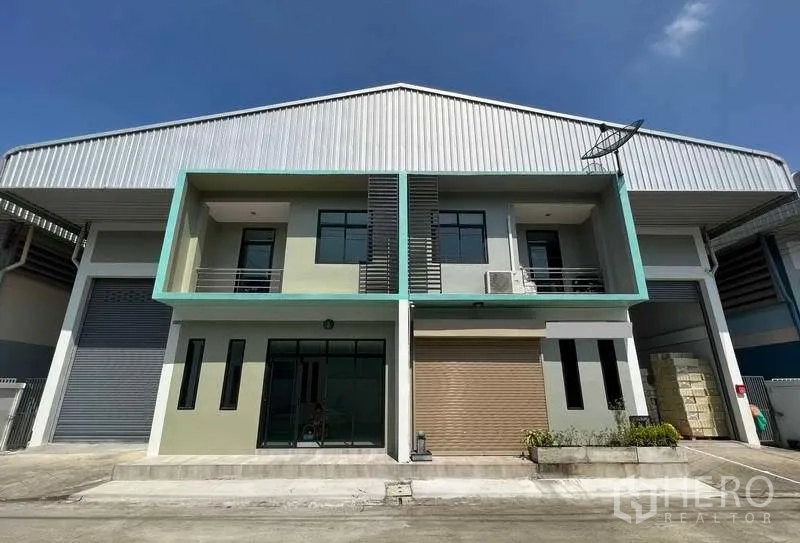 Factory for rent or sale in Mueang Samut Sakhon, Samut Sakhon - Modern factory exterior with two-storey office, large roller shutter and glass entrance under a metal roof.