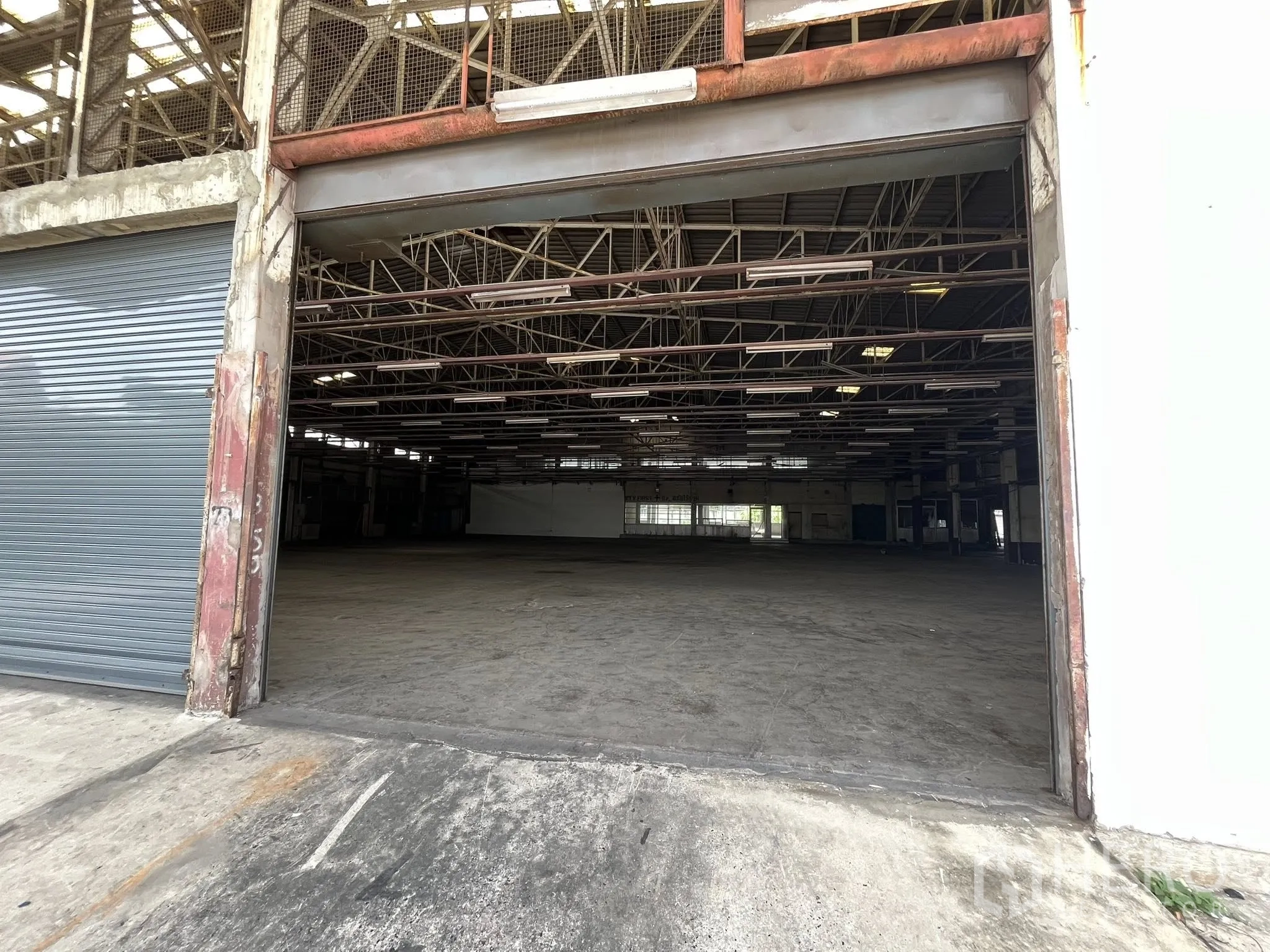 Factory for rent in Phra Pradaeng, Samut Prakan - Wide roller door entrance opening to a spacious warehouse interior.