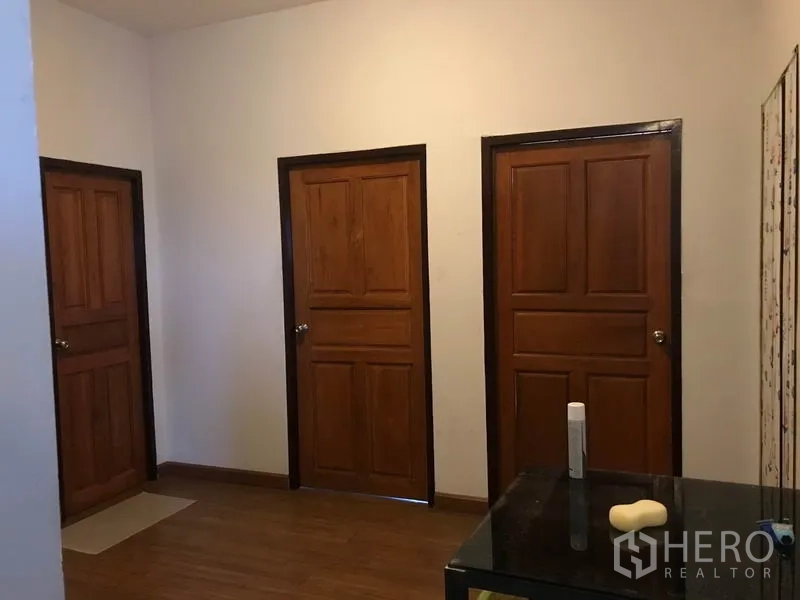Warehouse for rent in Khlong Sam Wa, Bangkok - Hallway featuring three wooden doors leading to private offices or storage rooms.