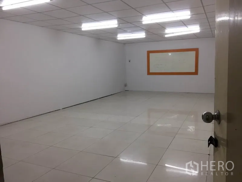 Factory for rent in Lam Luk Ka, Pathum Thani - Well-lit multipurpose room with grid ceiling lights and clean white tiled floor.
