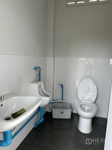 Warehouse for rent in Wang Noi, Phra Nakhon Si Ayutthaya - Warehouse restroom with sink, urinal, and toilet in a tiled room.