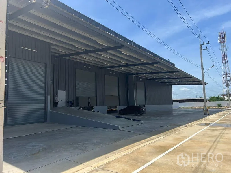 Factory for rent in Bang Pakong, Chachoengsao - Exterior loading zone with long roof canopy, truck ramp, multiple roller doors and wide driveway.