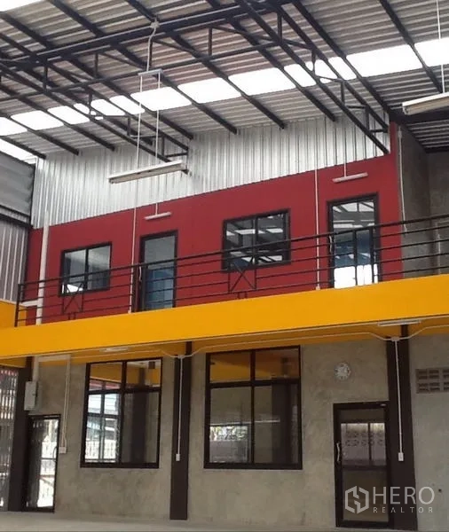 Warehouse for rent in Bang Kapi, Bangkok - Mezzanine level offices with red facade, metal roof and industrial lighting.