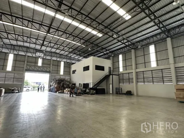 Warehouse for rent in Bang Phli, Samut Prakan - Warehouse hall featuring a two-storey internal office, staircase and a large loading door opening to the driveway.