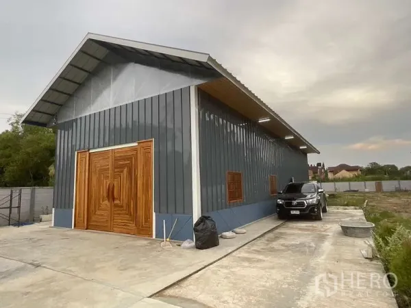 Warehouse for rent or sale in Nong Chok, Bangkok - Angled exterior of long metal‑clad warehouse with parking space and exterior lights on a concrete apron.