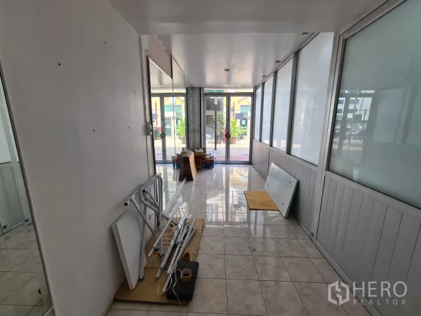 Shophouse for rent or sale in Sathon, Bangkok - Ground-floor retail area with tiled floor, frosted glass partitions and a glass entrance looking to the plaza.