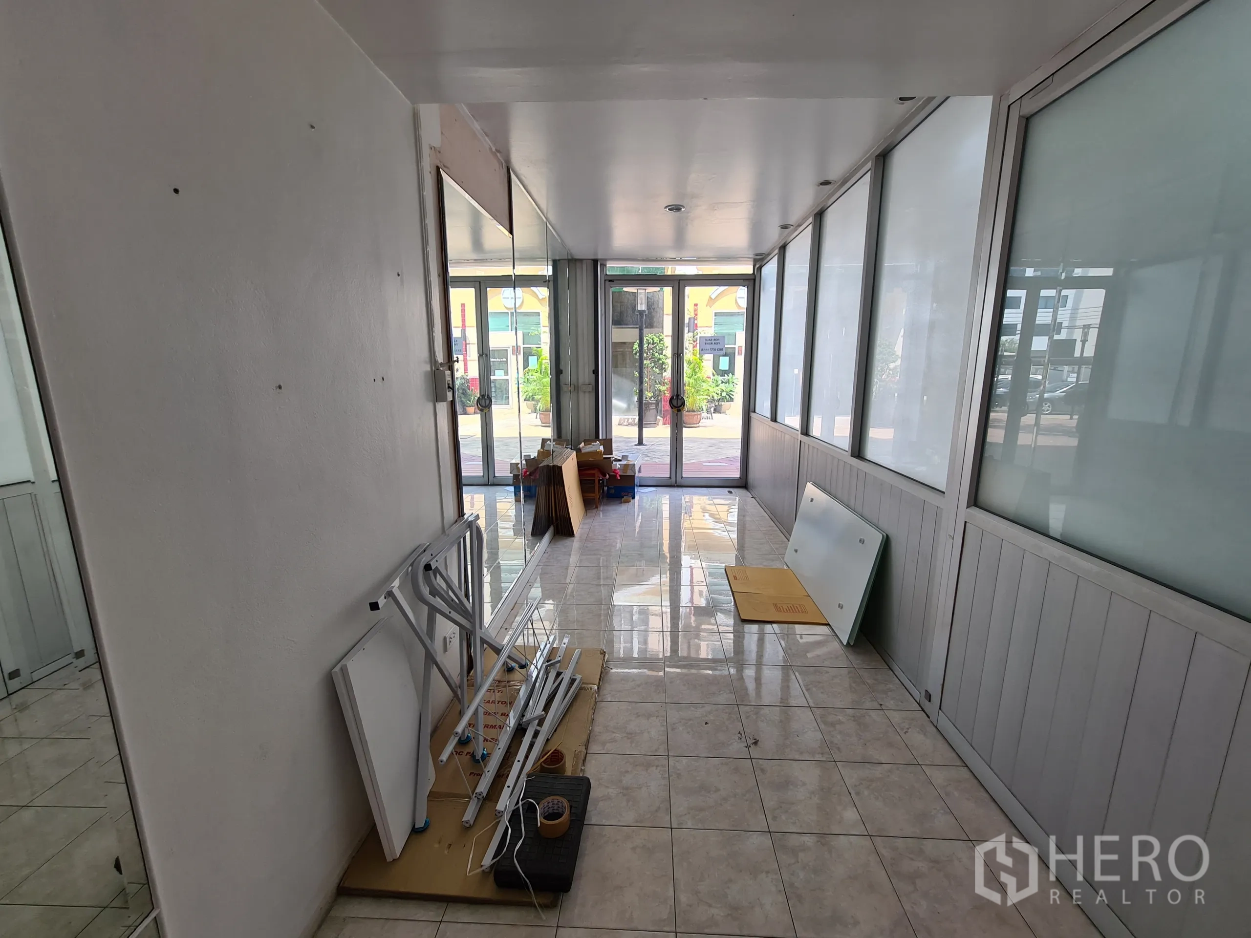 Shophouse for rent or sale in Sathon, Bangkok - Ground-floor retail area with tiled floor, frosted glass partitions and a glass entrance looking to the plaza.