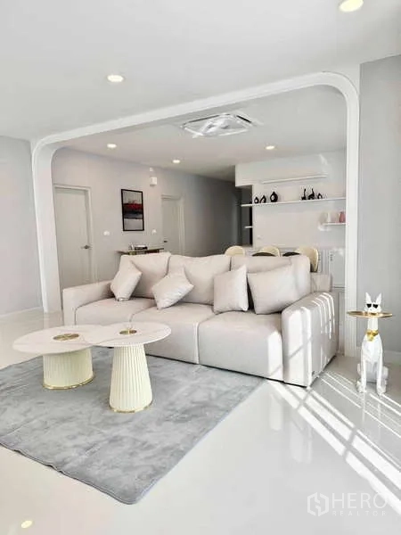 Detached House for rent or sale in Bang Phli, Samut Prakan - Bright living room with a white sofa, twin round coffee tables and an arched opening.