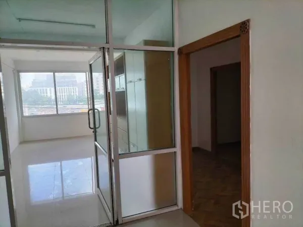 Shophouse for rent in Khlong Toei, Bangkok - Glass-partitioned office room with built-in cabinets and wide city-view windows.