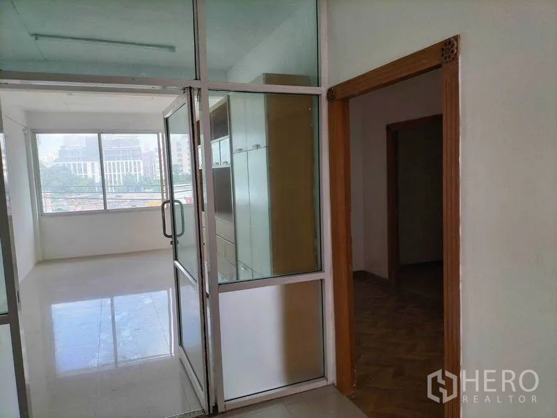 Shophouse for rent in Khlong Toei, Bangkok - Glass-partitioned office room with built-in cabinets and wide city-view windows.