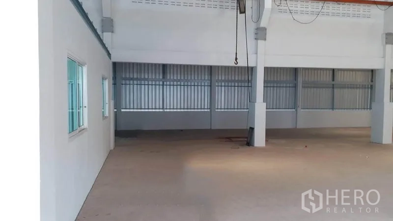 Factory for rent in Krathum Baen, Samut Sakhon - Spacious warehouse interior with high ceiling, concrete floor and metal cladding along the side wall.