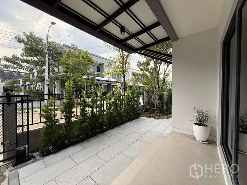 Detached House for sale in Bang Phli, Samut Prakan - Covered front terrace with tiled floor and privacy greenery along the fence.
