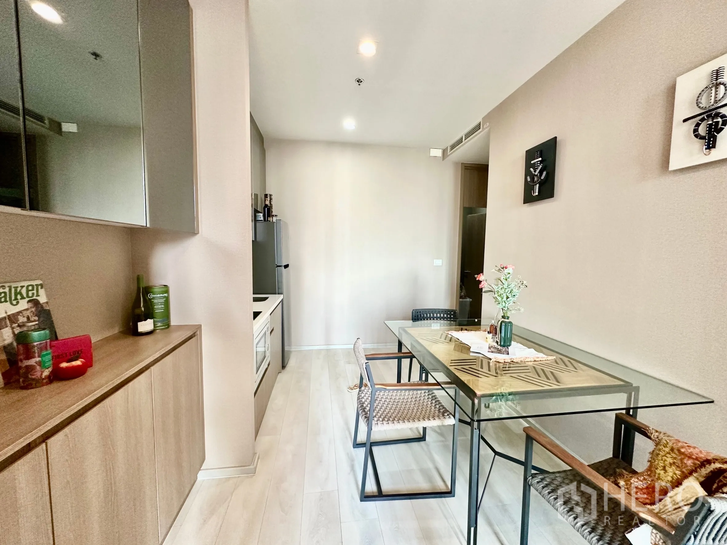Condominium for rent in Pathum Wan, Bangkok - Dining corner with glass-top table, minimalist cabinetry and light wood flooring.