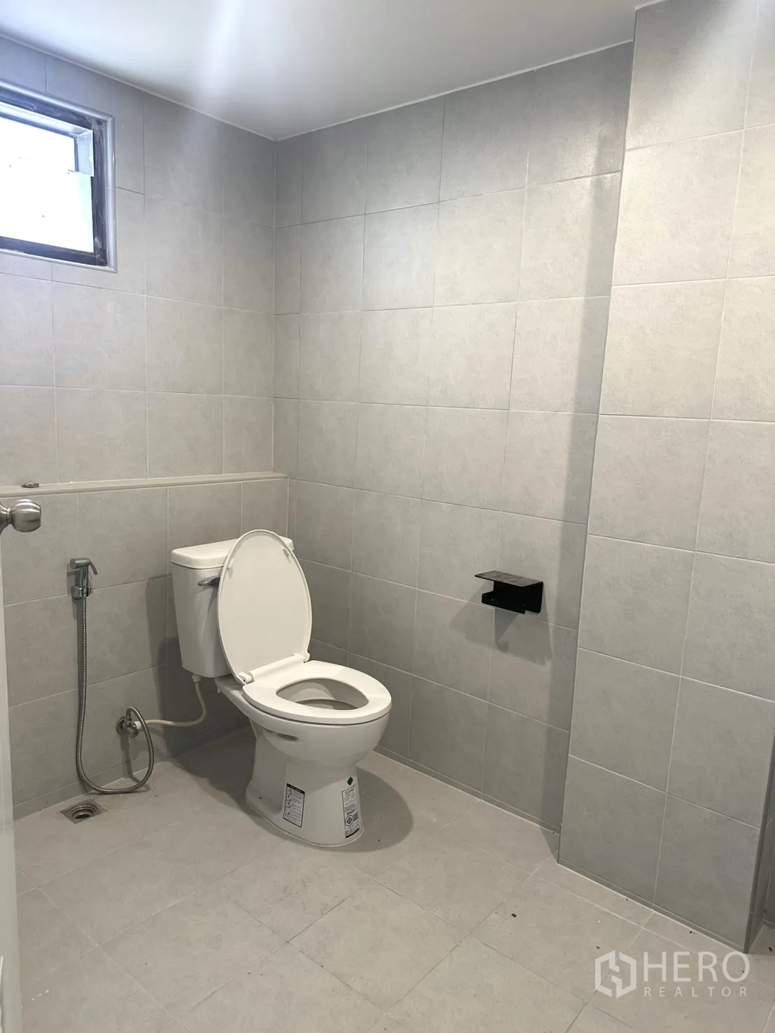 Warehouse for rent in Bang Phli, Samut Prakan - Renovated restroom with toilet, spray hose and tiled walls.