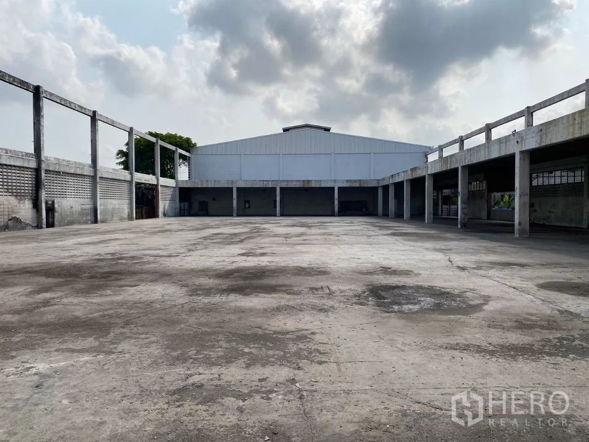 工厂 出售在Bang Phli, Samut Prakan - 中心混凝土院场被有顶月台环绕，尽头为白色金属屋顶仓库。