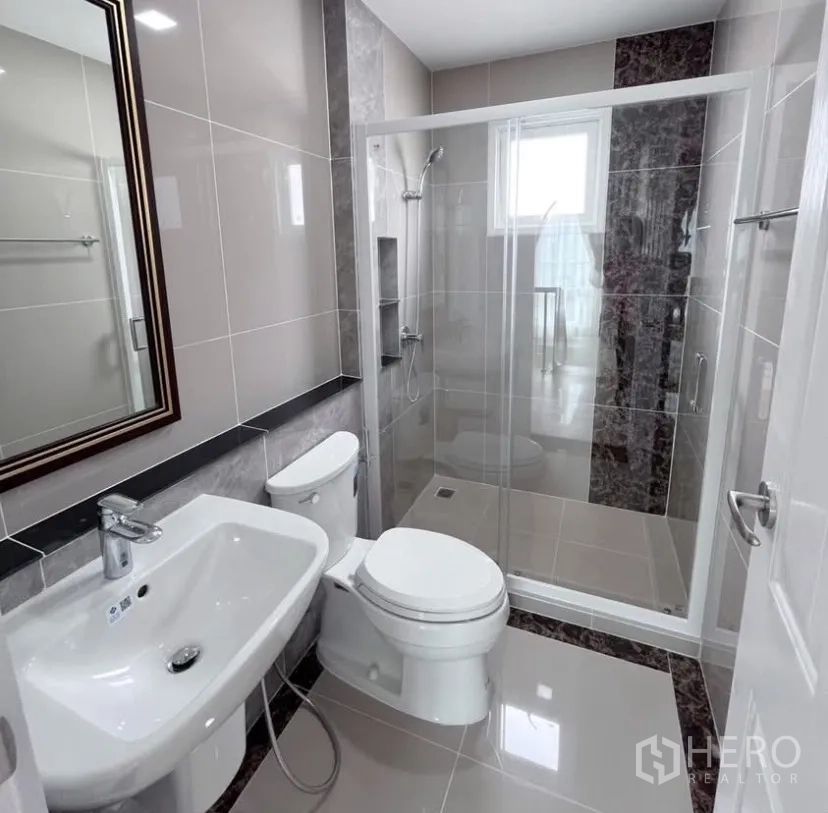 Detached House for rent in Mueang Samut Prakan, Samut Prakan - Modern bathroom with glass-enclosed shower, wall tiles, sink and toilet in a Samut Prakan detached house.